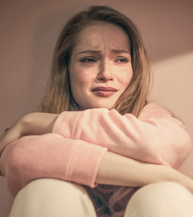 Thea sitzt weinend auf dem Boden und hat die Arme vor sich verschränkt.