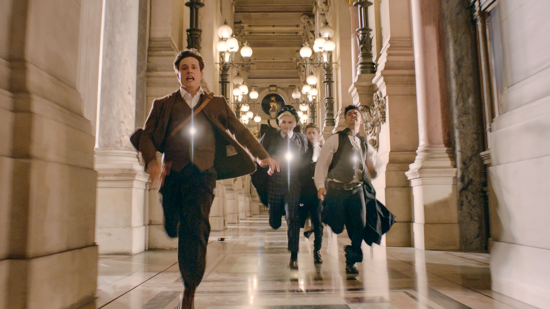 Henri (links im Bild) rennt durch einen langen Flur in der Opera Garnier. Hinter ihm her laufen die Zeitsammler, die ihn fangen wollen. 