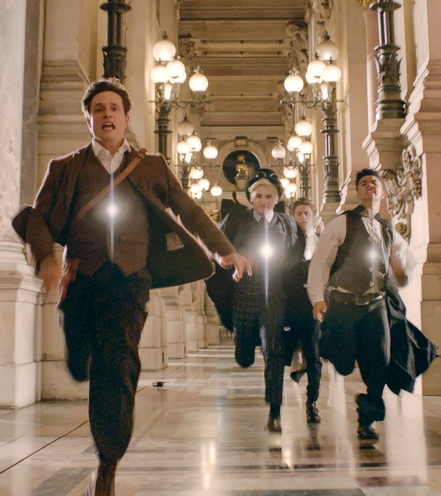 Henri (links im Bild) rennt durch einen langen Flur in der Opera Garnier. Hinter ihm her laufen die Zeitsammler, die ihn fangen wollen. 