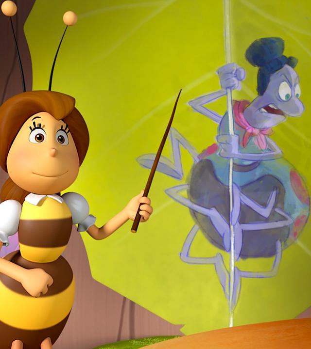 Die Lehrerin zeigt mit ihrem Zeigestock auf eine Abbildung von Spinne Thekla, die fluchend an einem Spinnenfaden hängt.