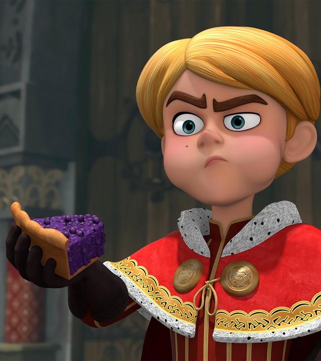 Prinz John (Mitte) hält ein großes Stück Blaubeerkuchen in seiner Hand. Er kaut gerade an einem Stück, das er abgebissen hat. Dabei blickt er verwundert nach vorne.