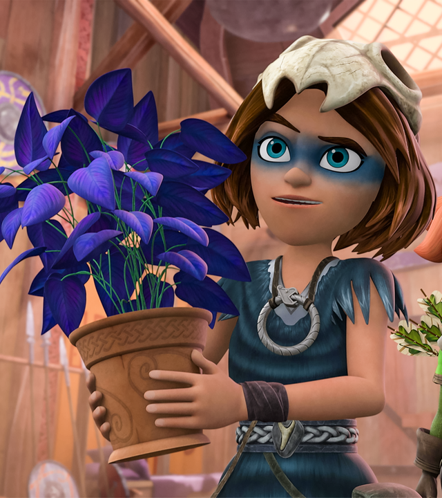 Im Wohnhaus der Wikinger hält Stig eine Pflanze in einem Tontopf in den Händen und präsentiert sie jemandem. Die Pflanze hat grüne Blumenstiele, ihre Blätter sind blau-violett. Robin steht hinter ihm und blickt skeptisch.