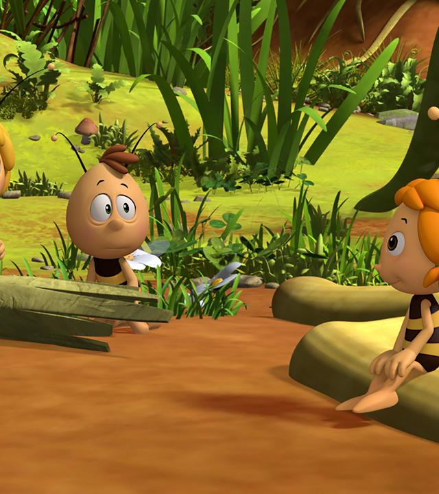 Maja und Willi zeigen einem Bienenschüler die Wiese. Dieser sitzt auf einem Baumstamm.