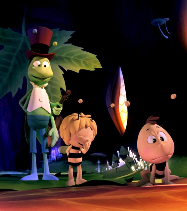 Willi, Maja und Flip bei Nacht im Bienenstock. Die Bienenwaben strahlen Licht aus und beleuchten den Platz.