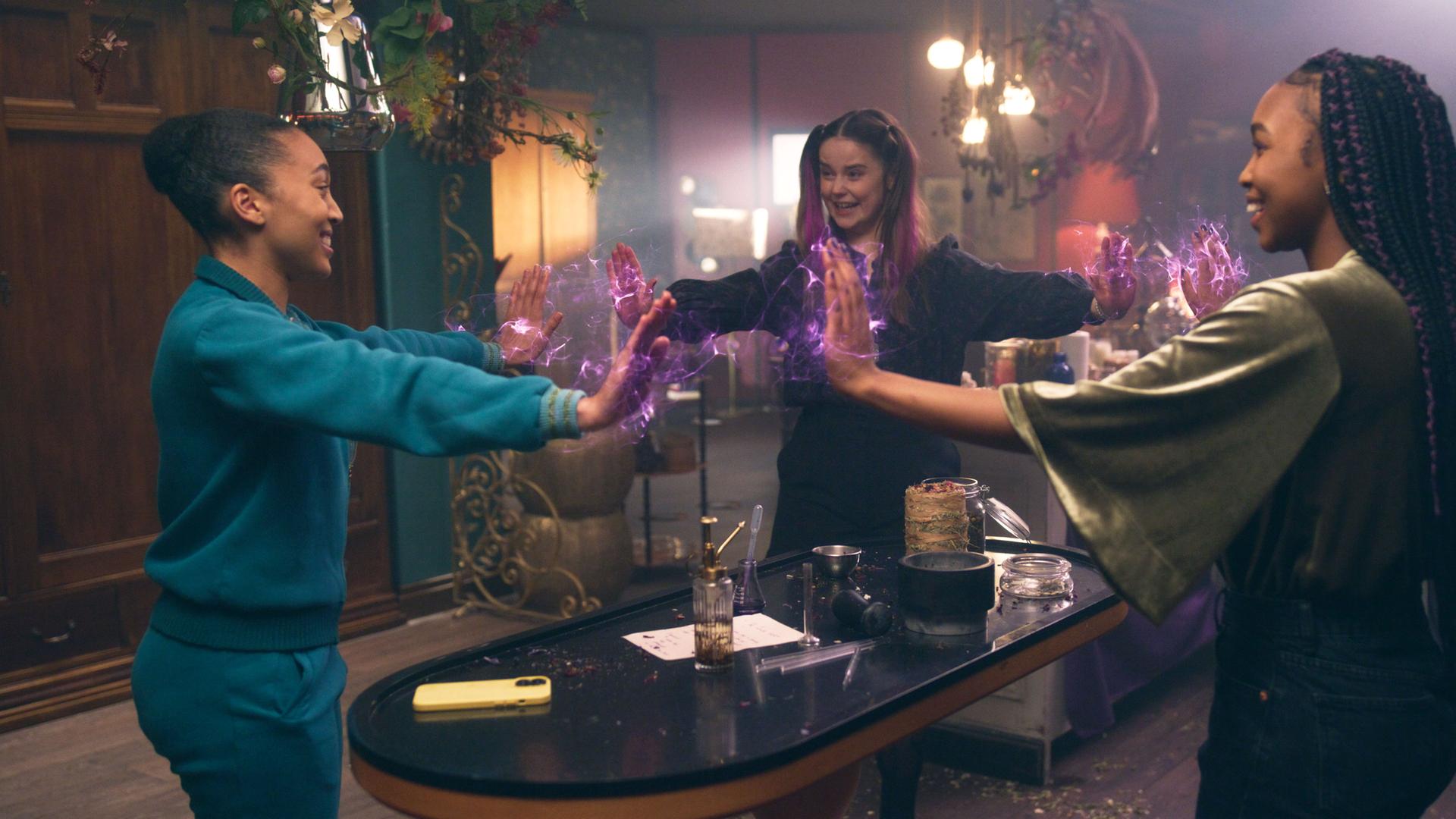 Cece, Lola und Amy stehen im Kreis mit ausgestreckten Armen und studieren gemeinsam einen Zauber ein.
