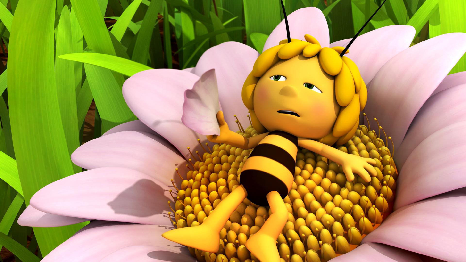 Maja liegt erschöpft und mit ausgestreckten Armen auf einer Blume. Dabei fächelt sie sich mit einer Blüte Luft zu.