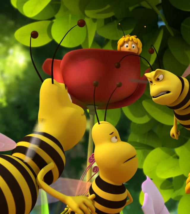 Jesper wehrt sich gegen die Wespenbande. Maja versteckt sich im Hintergrund hinter einer Blume.