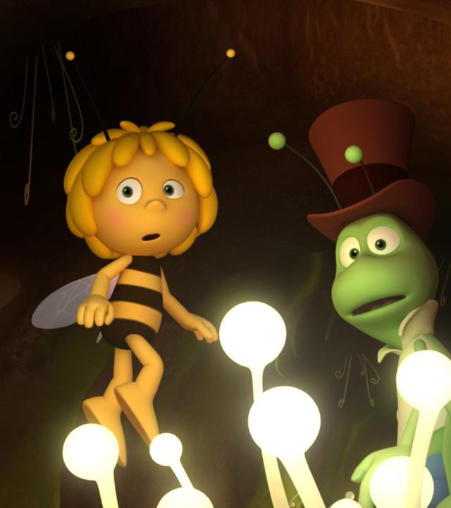 Maja und Flip sind in einem dunklen Erdloch unterwegs. Einzig weiße Lichtpflanzen weisen ihnen den Weg.