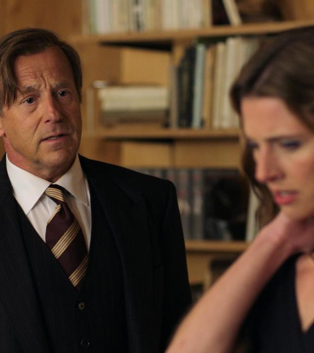 Roland (Heino Ferch) spricht streng zu seiner Tochter (Svenja Jung). Beide sind schick gekleidet: Er in einem Anzug, sie in einem Cocktailkleid.