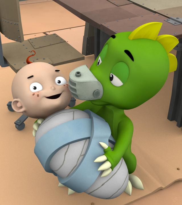 Drache Koks hält das grinsende Baby im Arm.