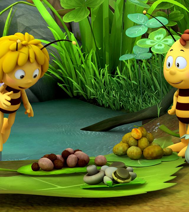 Biene Maja und Willi beim Picknick. Sie starren fröhlich auf ihr Picknick aus Pilzen und Nüssen, das vor ihnen auf Blättern liegt.