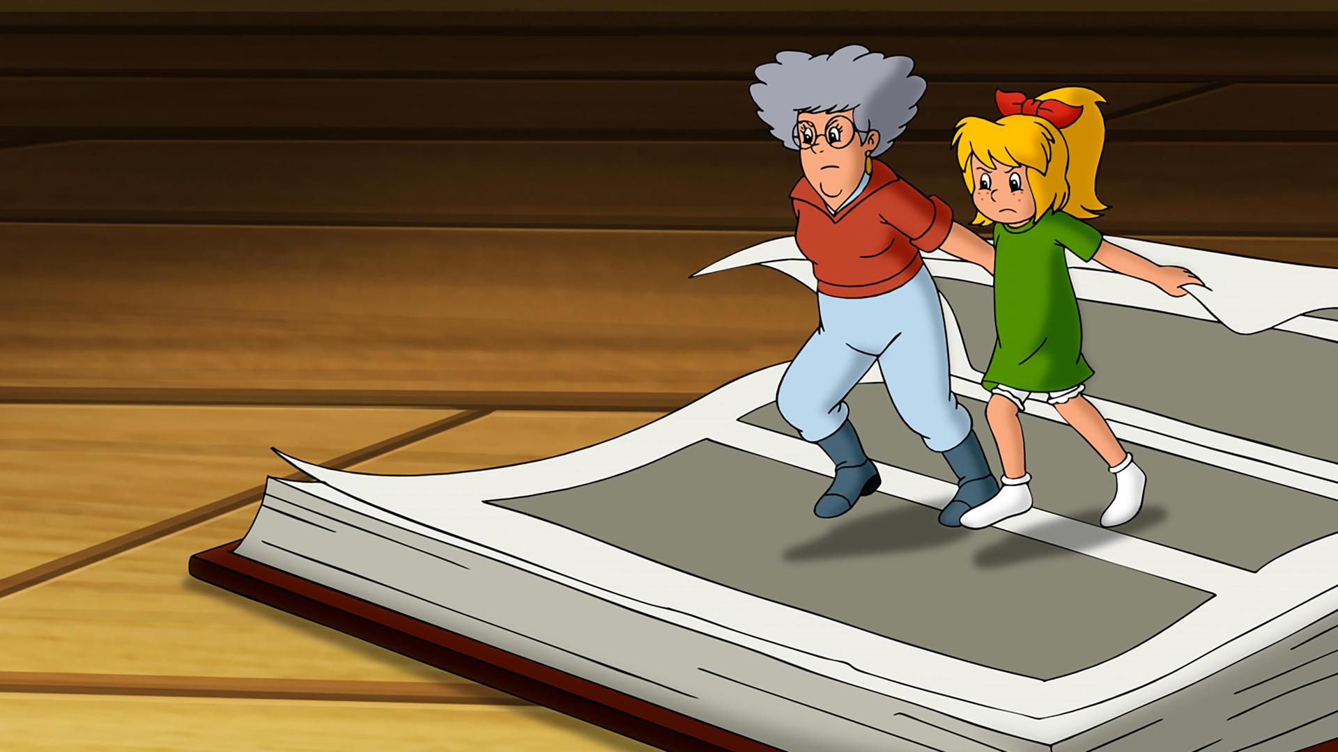 Oma Grete (links) und Bibi (rechts) sind kleingehext und versuchen mit aller Kraft im großen Hexbuch zu blättern, indem sie zusammen an einer Seite ziehen.