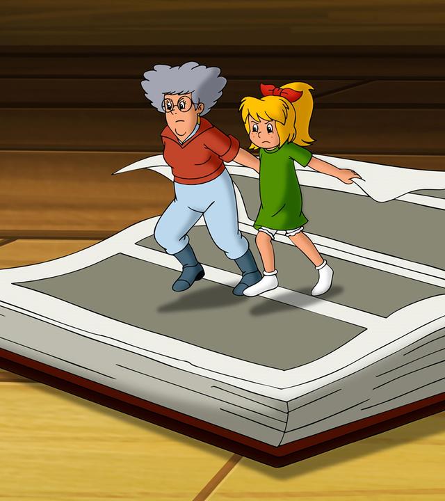 Oma Grete (links) und Bibi (rechts) sind kleingehext und versuchen mit aller Kraft im großen Hexbuch zu blättern, indem sie zusammen an einer Seite ziehen.