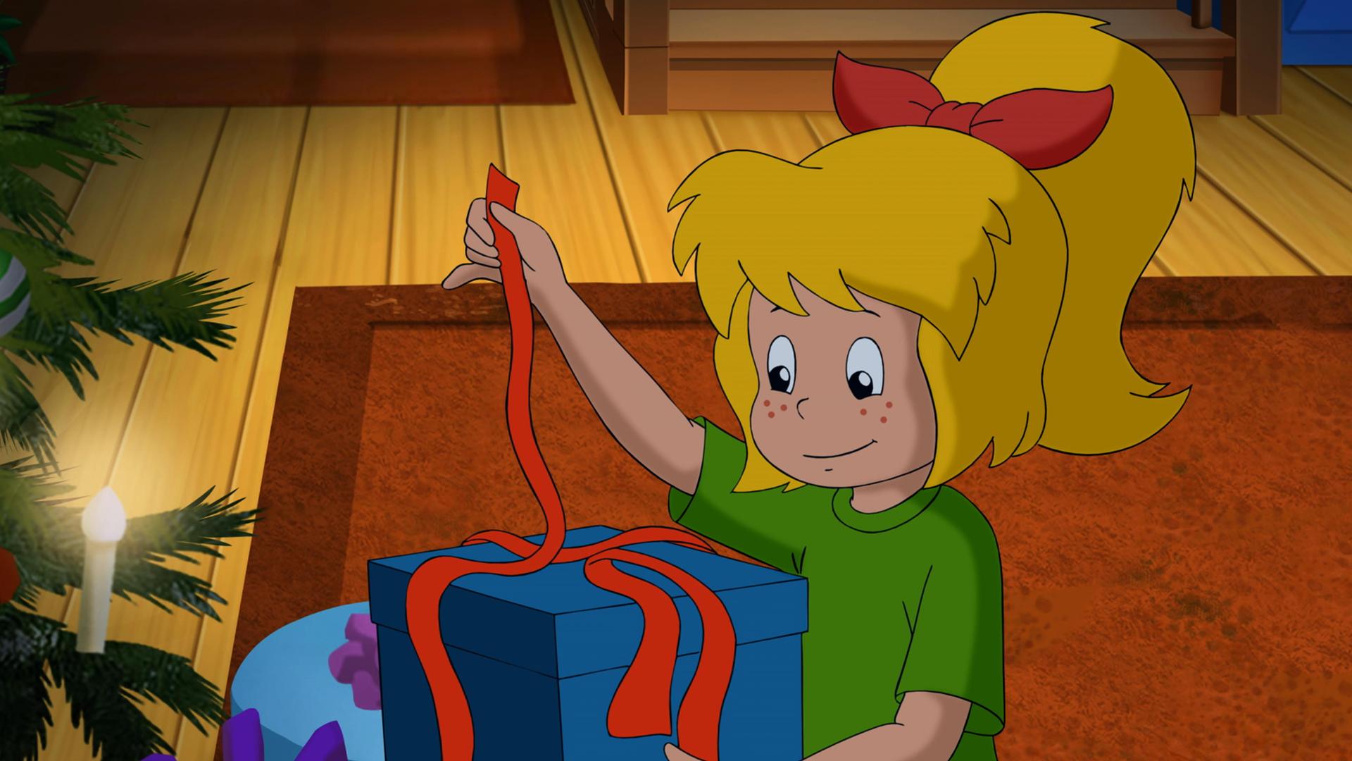 An Heiligabend packt Bibi ein blaues Paket mit einer roten Schleife aus Irland aus.