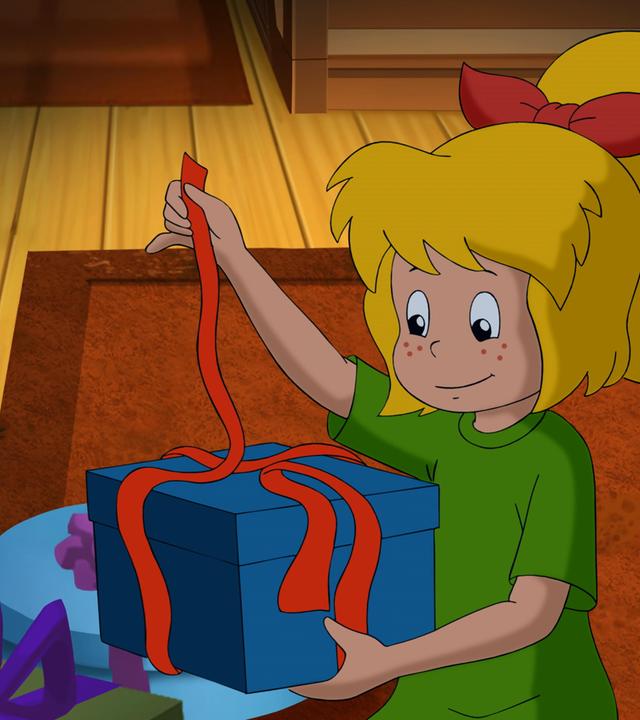 An Heiligabend packt Bibi ein blaues Paket mit einer roten Schleife aus Irland aus.