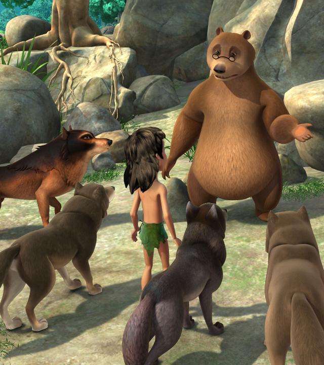 Balu steht vor dem Wolfrudel. Rechts neben ihm kauert der kranke Akela. Mogli und vier Wölfe stehen Balu gegenüber und hören im zu.