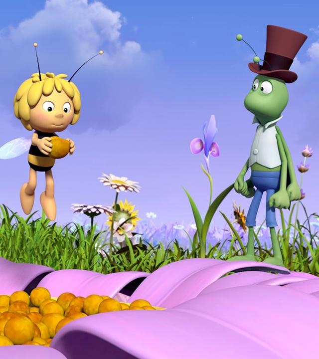 Maja hält einen großen Blumensamen in den Händen. Flip schaut ihn an.