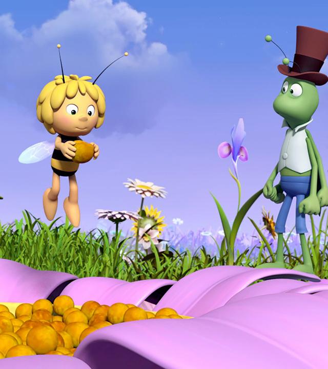 Maja hält einen großen Blumensamen in den Händen. Flip schaut ihn an.