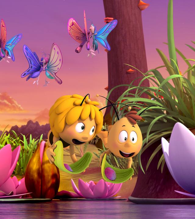 Willi und Maja fliegen glücklich nebeneinander und tragen bunte Blüten auf Blättern. Begleitet werden sie dabei von vielen bunten Schmetterlingen.