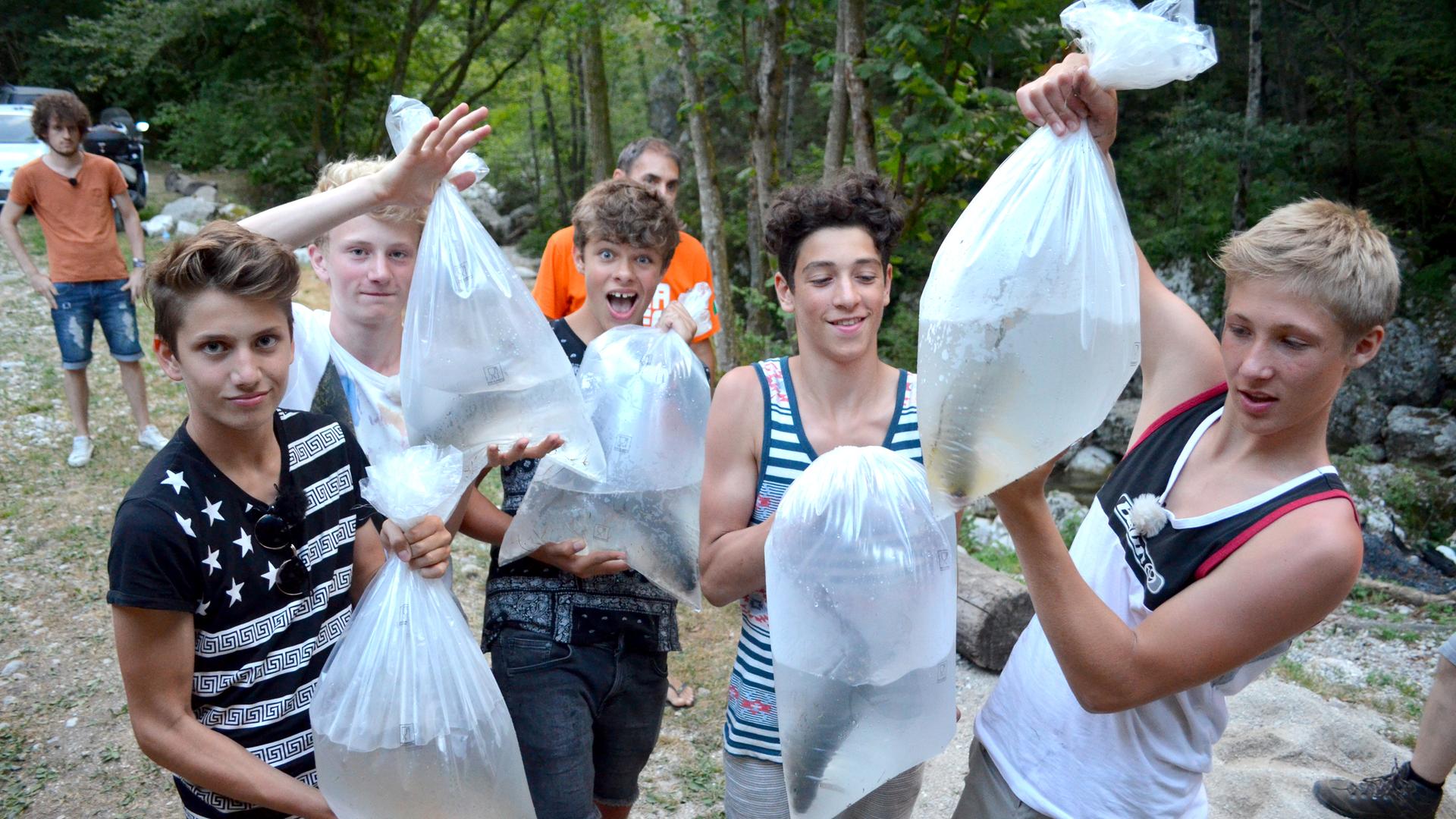 Die Jungs tragen Wasserbeutel mit Fischen darin.