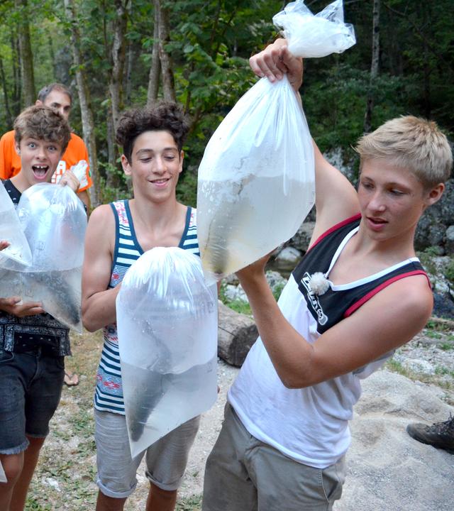 Die Jungs tragen Wasserbeutel mit Fischen darin.