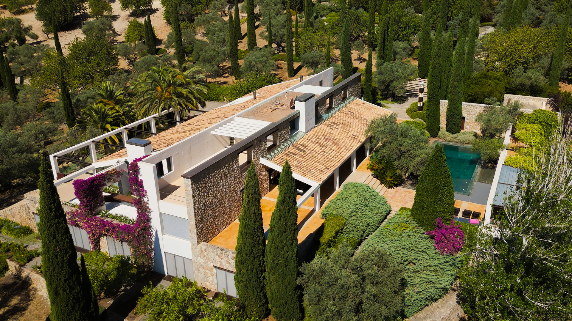 Blick aus der Vogelperspektive auf eine Villa, umgeben von Bäumen