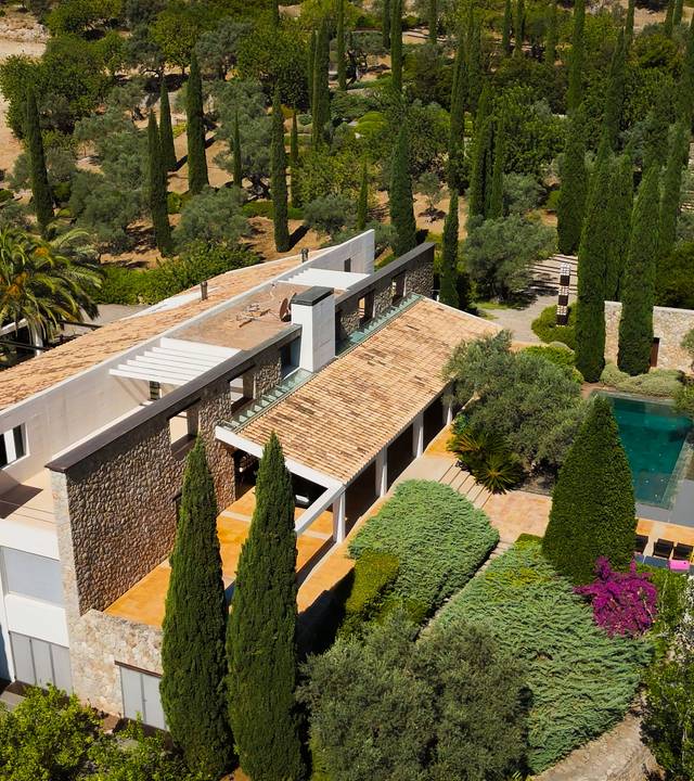 Blick aus der Vogelperspektive auf eine Villa, umgeben von Bäumen