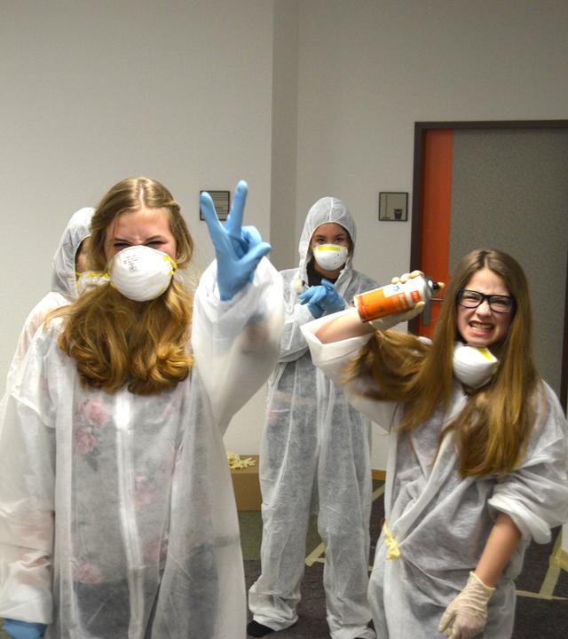 Die Mädels sind in weißer Schutzkleidung und halten Sprühdosen bereit