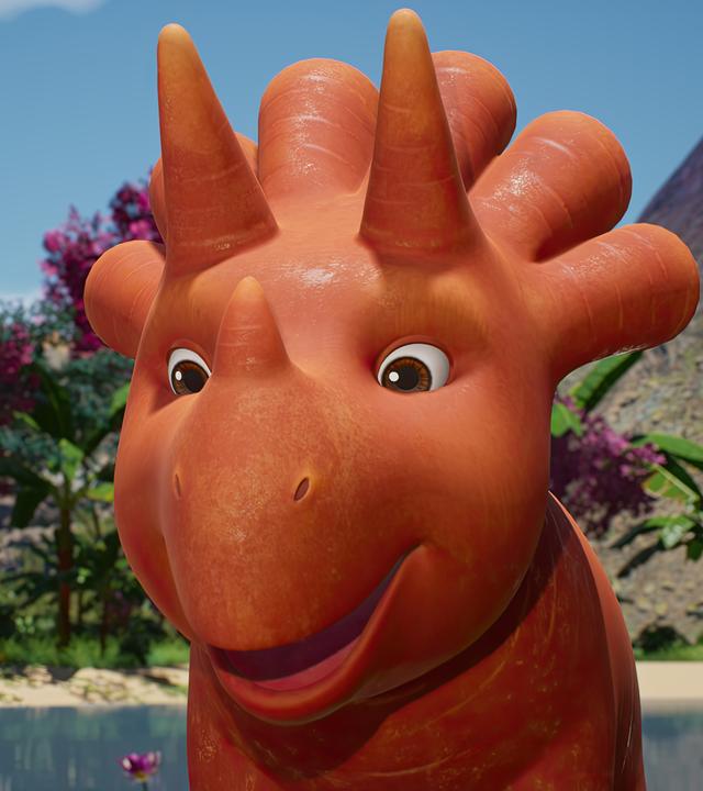 Ginger, ein Trikarottops-Mädchen, das aussieht wie eine Mischung aus Karotte und Nashorn, steht freudestrahlend vor Bananenstauden und im Hintergrund ist ein Vulkan zu sehen.