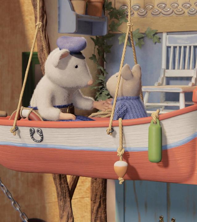 Opa Seemann und Sam sitzen sich in einem kleinen Boot gegenüber, das an zwei Seilen von der Decke im Hof des Mäusehauses hängt. Hinter ihnen sieht man die Terrasse mit einem Schaukelstuhl und einer Tür, auf der ein Ankerzeichen hängt. Opa Seemann und Sam sind in ein Gespräch vertieft.