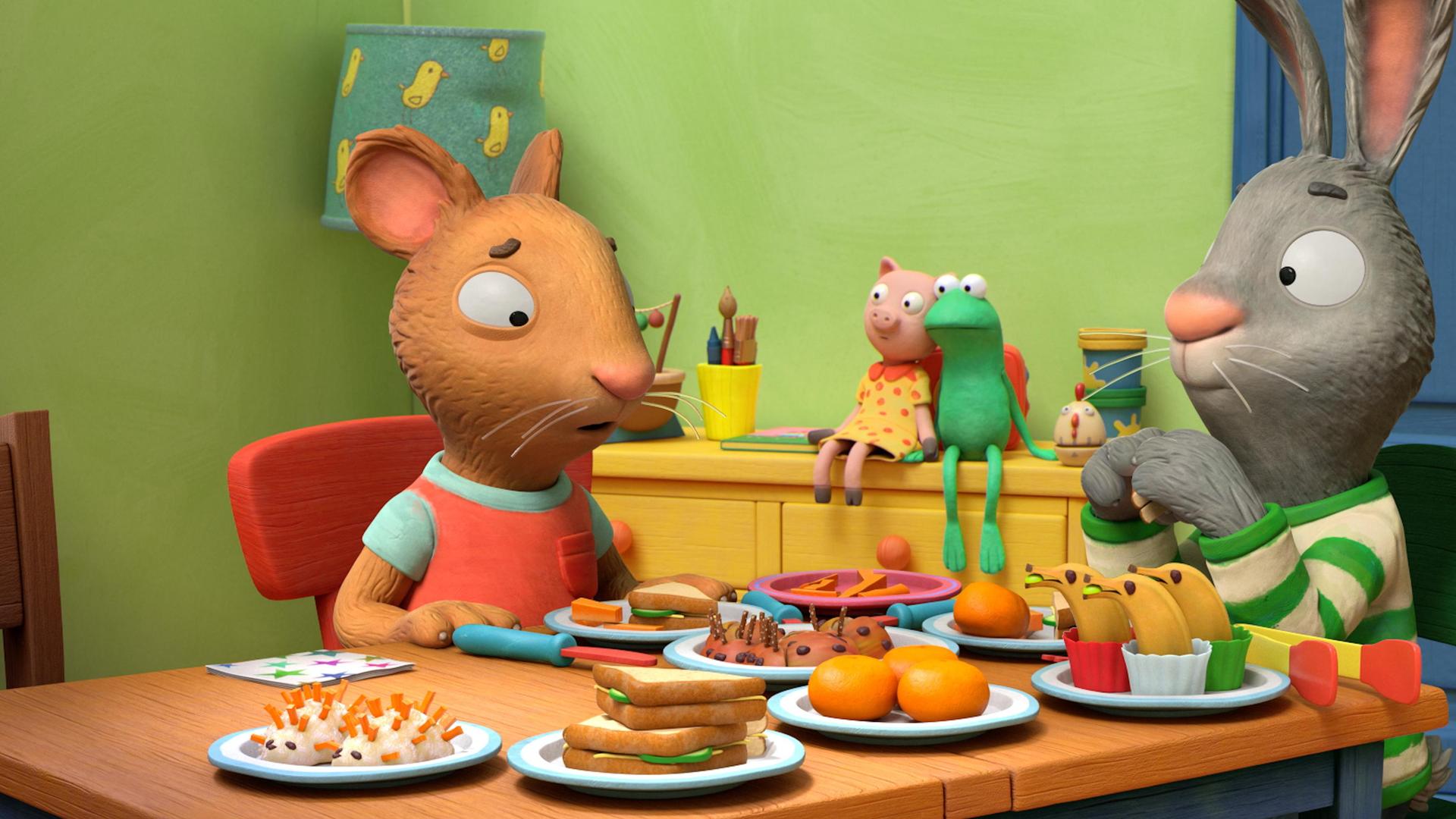 An einem reichlich gedeckten Tisch mit allerlei schön dekorierten Leckereien sitzen die zwei Freunde Posy, die Maus und Pip, das Kaninchen. Posy blickt mit traurigem Blick auf ihren gefüllten Teller. Pip blickt verwundert zu Posy.