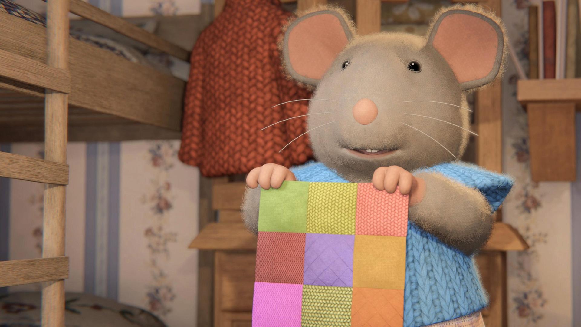 Sams Mutter steht im Kinderzimmer zwischen den Kinderbetten und hält ein buntes Patchwork-Viereck hoch.