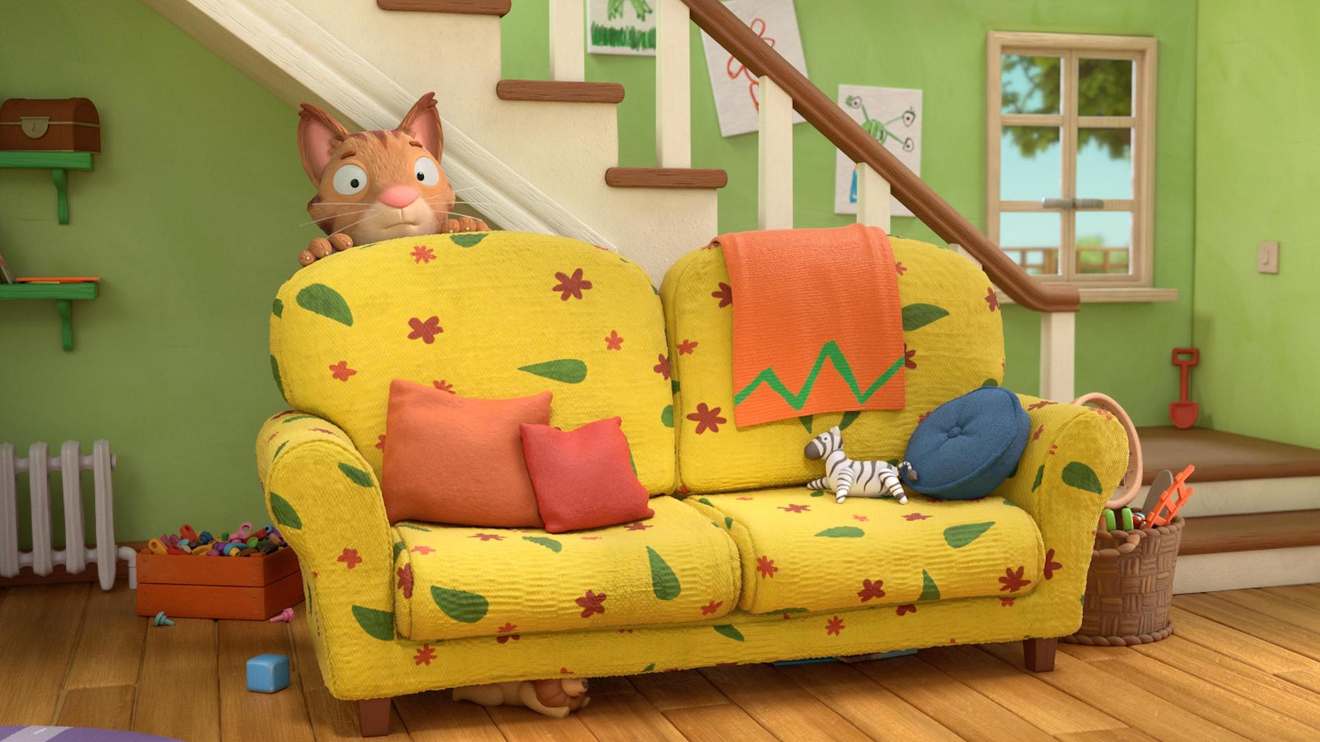Im Wohnzimmer hinter dem bunten Sofa versteckt sich Frankie, die Katze. Vorsichtig schaut sie hinter der hohen Lehne des Sofas hervor. Im Hintergrund  hängen bunte, selbst gemalte Bilder am Treppenaufgang und durch ein Fenster blickt man hinaus in den Garten.