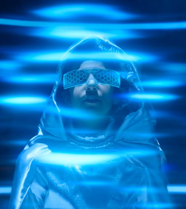 Bekleidet mit einem silbernen Weltraumanzug und spaciger Brille und umringt von blauen Strahlen, steht der neue Austauschschüler Juan da und schaut mit mystischem Blick nach vorne.