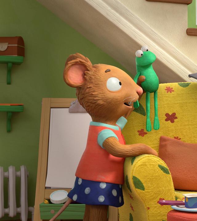 Posy, die Maus hält ihr Lieblingsspielzeug, das Stofftier Froschi in Höhe der Sofalehne und sagt etwas zu Pip. Pip, das Kaninchen, kniet seitlich auf dem Sofa und spielt mit einem selbst gebauten, fliegenden Schweinchen-Wagen. Sein Lieblingsstofftier Schweinchen sitzt auf dem fliegenden Wagen obenauf.