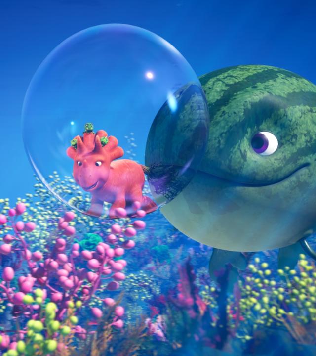Eine riesige grüne Melone mit Gesicht und Flossen - ein sogenannter Melonensuchus - schubst eine große Luftblase unter Wasser vor sich her. In der Luftblase eingeschlossen ist Ginger, das Dinosauriermädchen, das aussieht wie eine Karotte. Das Wasser ist tiefblau. Am Grund des Sees wachsen rosafarbene und grüne Pflanzen.