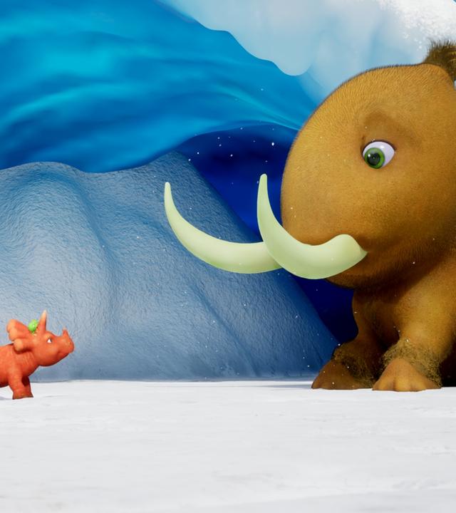 Ein Dinosaurier, der aussieht wie eine orangefarbene Karotte mit einem Schwanz aus Karottengrün, schaut überrascht. Es ist Ginger, das Trikarottops-Mädchen. Ginger steht einem viel größeren Kiwi-Mammut gegenüber. Das Kiwi-Mammut hat große Stoßzähne, aber der Körper sieht aus wie eine Kiwi. Sie stehen vor einer Höhle, die aus Eis besteht. Überall liegt Schnee. Das Eis in der Höhle schimmert bläulich.