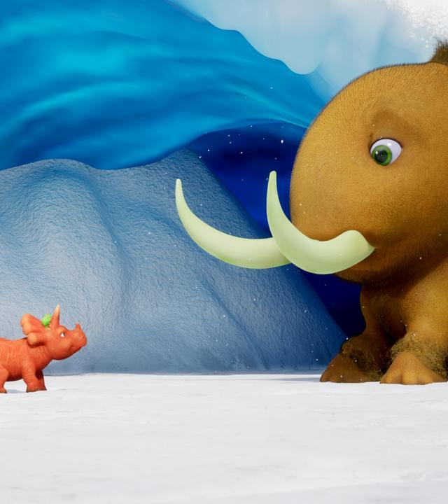 Ein Dinosaurier, der aussieht wie eine orangefarbene Karotte mit einem Schwanz aus Karottengrün, schaut überrascht. Es ist Ginger, das Trikarottops-Mädchen. Ginger steht einem viel größeren Kiwi-Mammut gegenüber. Das Kiwi-Mammut hat große Stoßzähne, aber der Körper sieht aus wie eine Kiwi. Sie stehen vor einer Höhle, die aus Eis besteht. Überall liegt Schnee. Das Eis in der Höhle schimmert bläulich.
