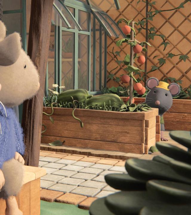 Julia und Sam sitzen nebeneinander auf einer Bank und schauen zu Tonio, der auf der anderen Seite des Hofes hinter einem Hochbeet sitzt. Neben Tonio steht ein Gewächshaus und hinter ihm ein weiteres Hochbeet. Dahinter hängt ein großes Rankgitter an der Wand.