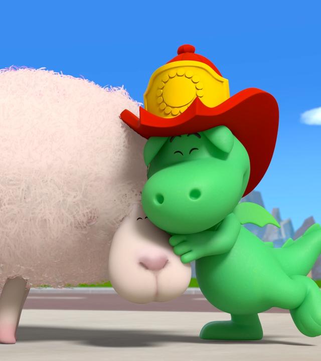 Der kleine grüne Drache Grisu mit seinem roten Feuerwehrhelm umarmt ein flauschiges Schaf.