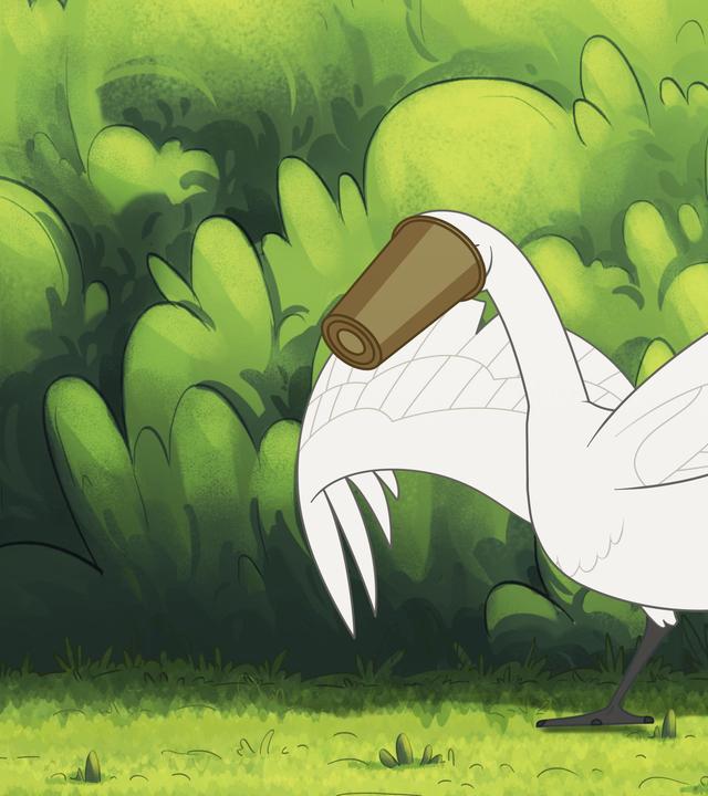 Ein großer, weißer Schwan steht auf grünem Rasen vor einer grünen Hecke und hat einen braunen Pappbecher über dem Kopf. Seine Flügel sind ausgebreitet.