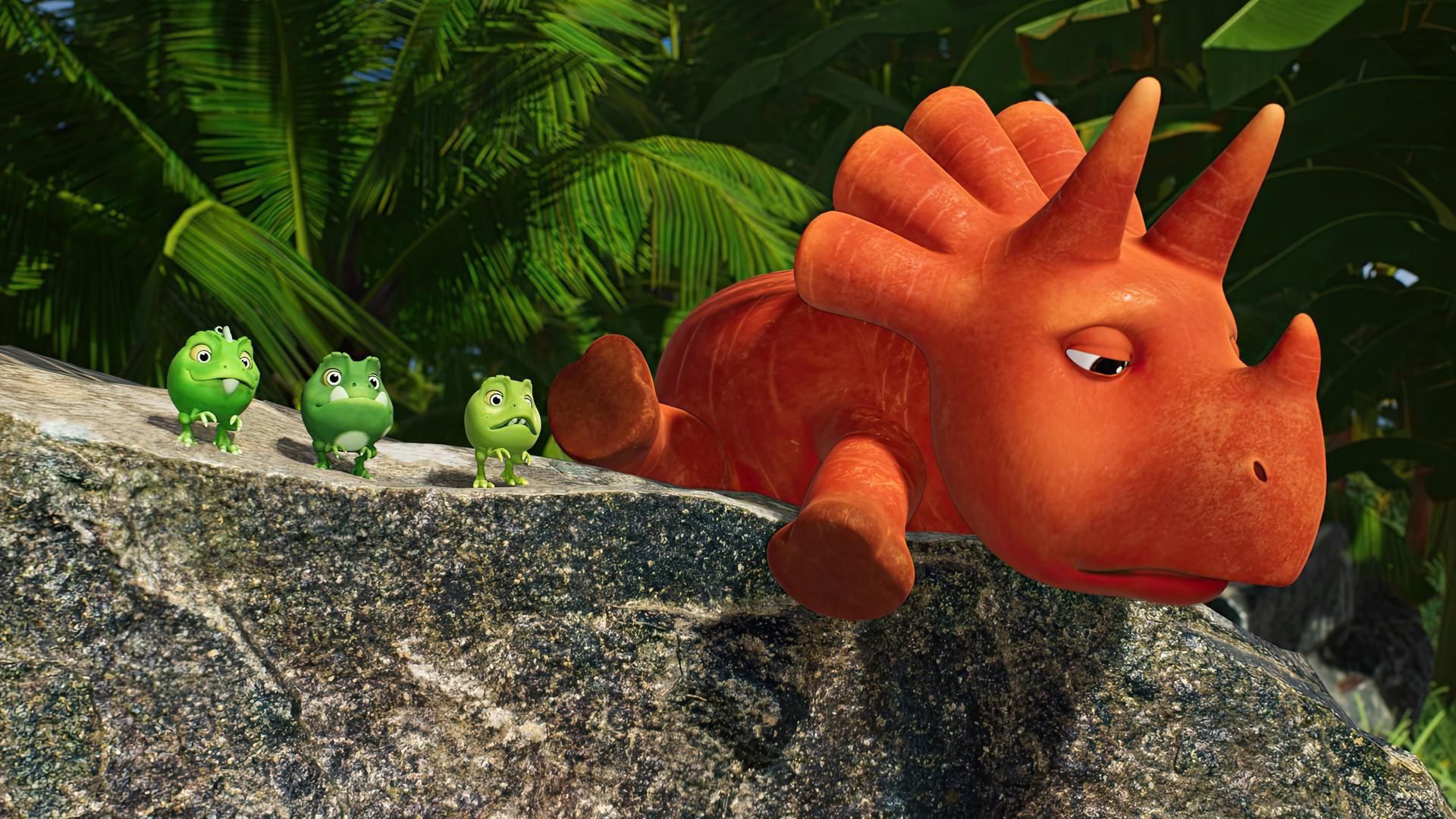 Auf einem Felsen liegt bäuchlings ein orangefarbener Dinosaurier, der aussieht wie eine Karotte, und streckt alle vier Beine von sich. Es ist das Trikarottops-Mädchen Ginger. Sie schaut traurig. Neben ihr stehen die Erbs-Rexe Minzi, Wasabi und Split.