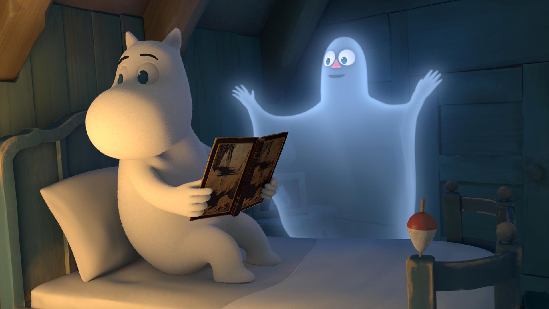 Mumin sitzt auf seinem Bett und hält ein Buch in seinen Händen. Er merkt gar nicht, dass neben ihm ein Geist schwebt, der ihn erschrecken möchte.