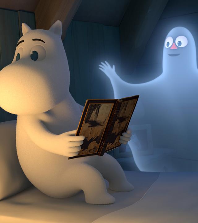 Mumin sitzt auf seinem Bett und hält ein Buch in seinen Händen. Er merkt gar nicht, dass neben ihm ein Geist schwebt, der ihn erschrecken möchte.