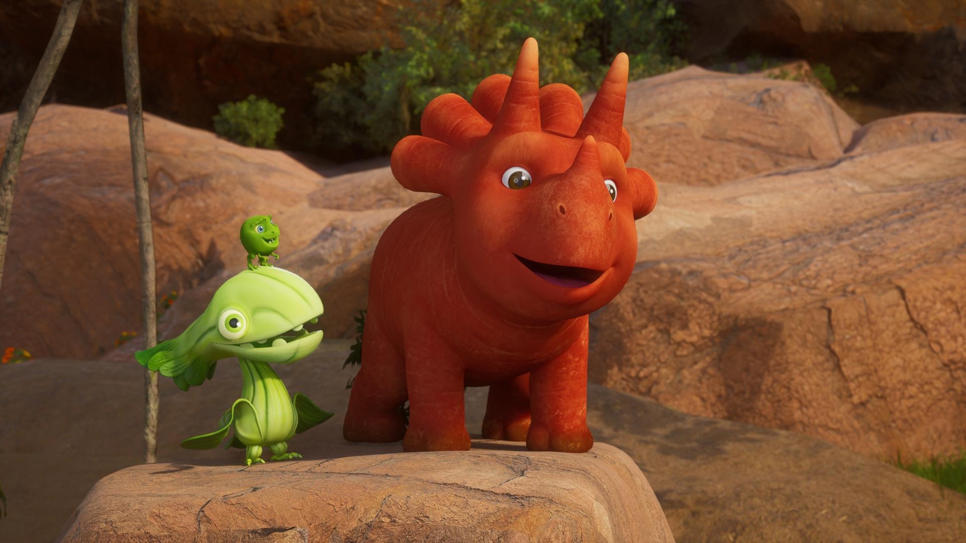 Auf einem erhöhten Felsen stehen Ginger, das Trikarottops-Mädchen und ein Pakchoidactylus. Auf dem Kopf des Asia-Kohl-Vogels sitzt ein Erbs-Rex. Sie schauen beide Ginger an - und Ginger macht ein fröhliches Gesicht.