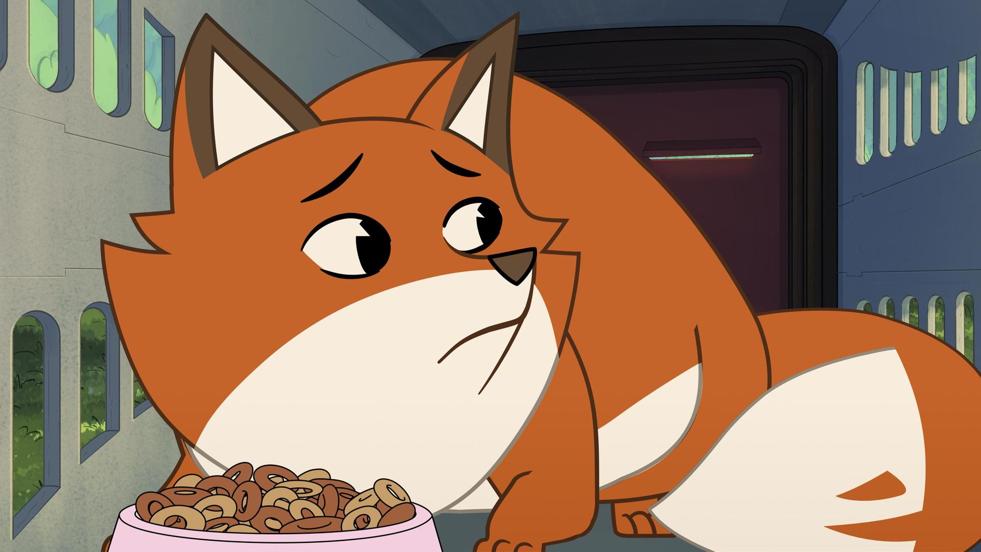 Der orangefarbene Fuchs Iwo ist in einer Transportkiste für Katzen eingesperrt. Die Kiste hat an der Seite kleine Luftschlitze. Iwo duckt sich mit ängstlichem Blick auf den Boden der kleinen Box. Vor ihm steht eine rosafarbene Schüssel mit Trockenfutter in Form von kleinen braunen Kringeln.
