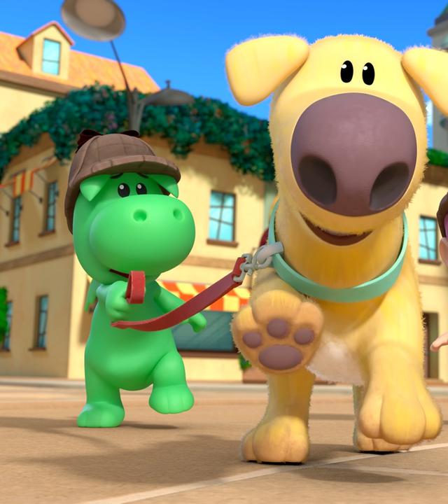 Drache Grisu und seine Freundin Stella jagen mit dem Hund Dinki durch eine Straße von Drachenstadt. Der Hund Dinki rennt voraus. Grisu und Stella tragen Mützen wie Sherlock Holmes.