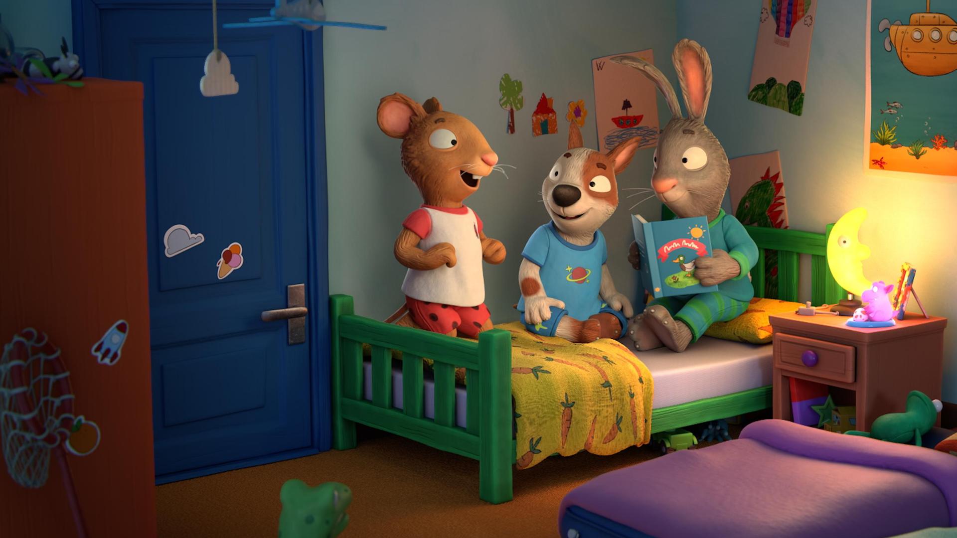 Abends im Zimmer während einer Übernachtungsparty: Die drei Freunde Posy, die Maus, Zac, der Hund, und Pip, das Kaninchen, haben es sich gemeinsam auf einem Bett gemütlich gemacht. Pip liest eine Geschichte aus einem Buch vor. Zwei Gästebetten aus Luftpolstermatratzen liegen im Zimmer auf dem Boden. Auf dem Nachttisch leuchtet ein Mond als Nachttischlampe.