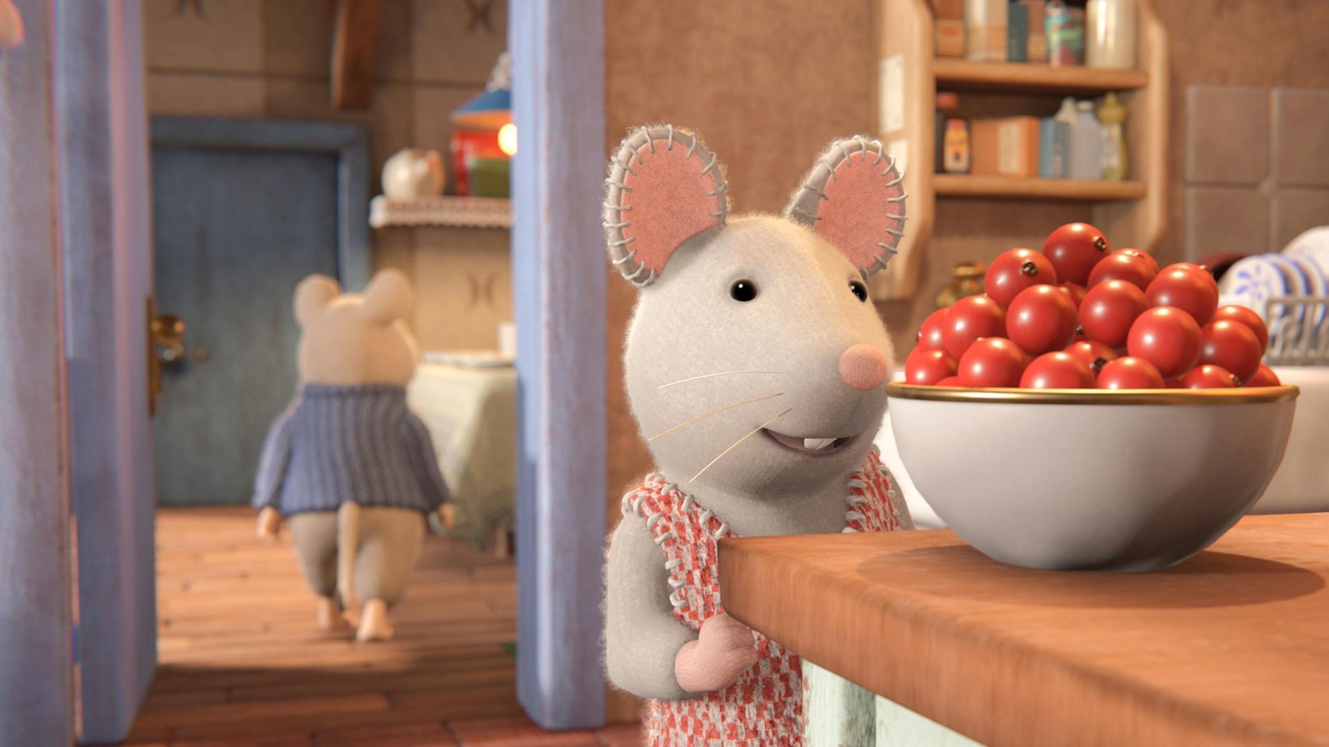 Julia steht in der Küche vor einer Schüssel mit roten Beeren auf einem Tisch und schaut sie begehrlich an. Hinter ihr verlässt Sam gerade die Küche. Er ist von hinten zu sehen und geht auf einen Tisch im Nebenraum zu.