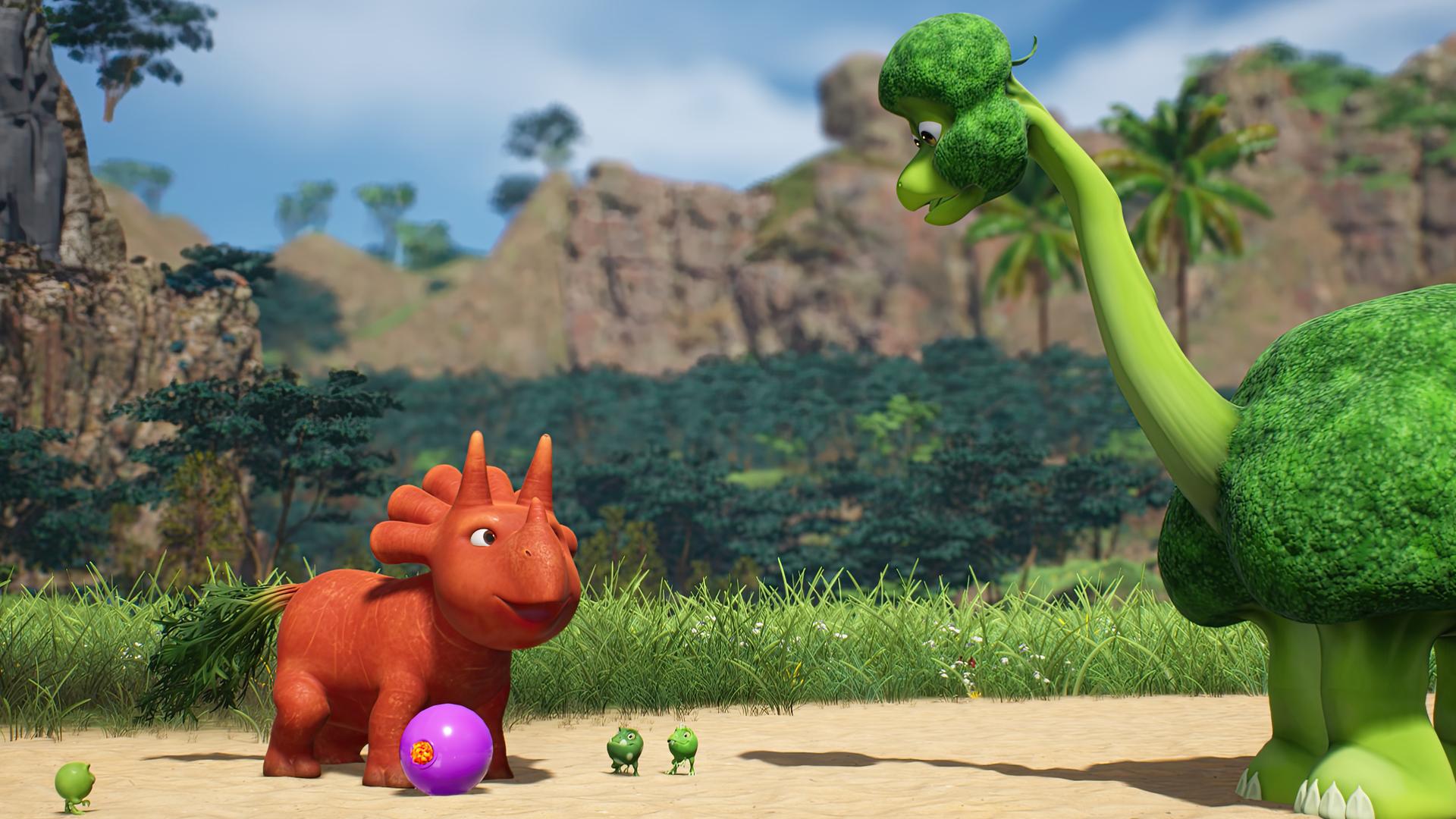 Ginger, das orangefarbene Trikarottops-Mädchen, hat einen violetten Fußball am Fuß. Sie scheint den Ball zu einem großen, grünen Brokkolisaurier kicken zu wollen, der ihr gegenüber steht. Mit dabei stehen die drei kleinen Erbs-Rexe.